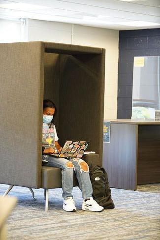 一名学生正在使用图书馆的新学习舱之一，这恰好也促进了身体距离.
